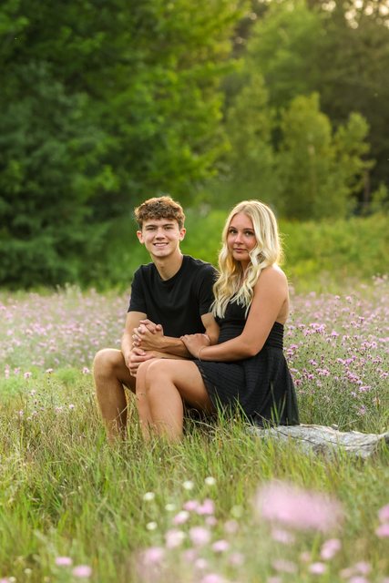 Couple seated together in a flower-filled meadow
