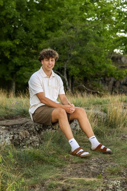 Portrait of a young man seated on a rock