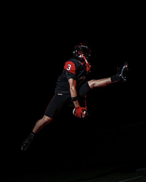 Football player kicking against a black background