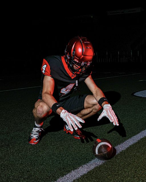 Football portrait kneeling over the ball in red lighting