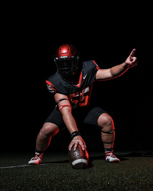 Football player pointing upward in dramatic red lighting