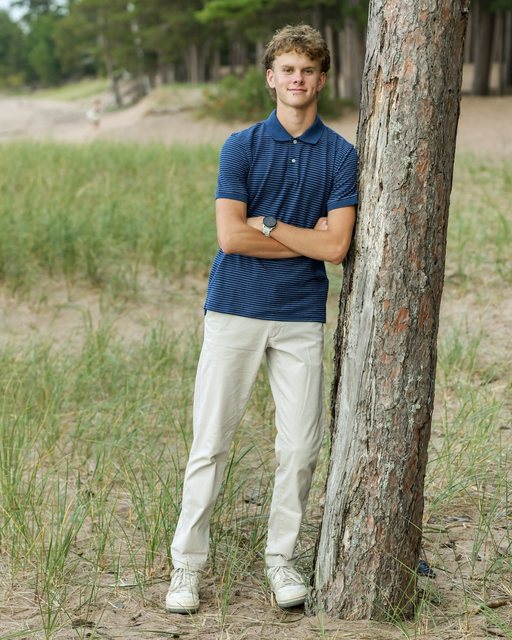 Portrait in a blue shirt beside a pine tree