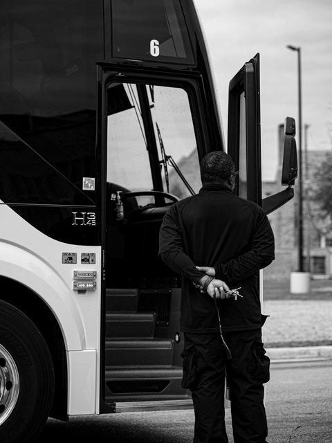 Black-and-white portrait beside a team bus