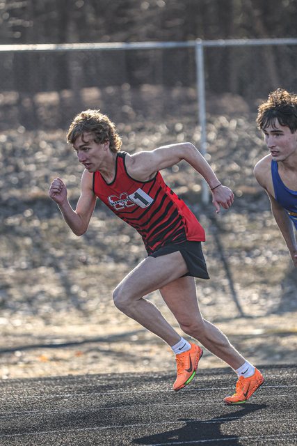Runner in a red jersey rounding the bend of a track